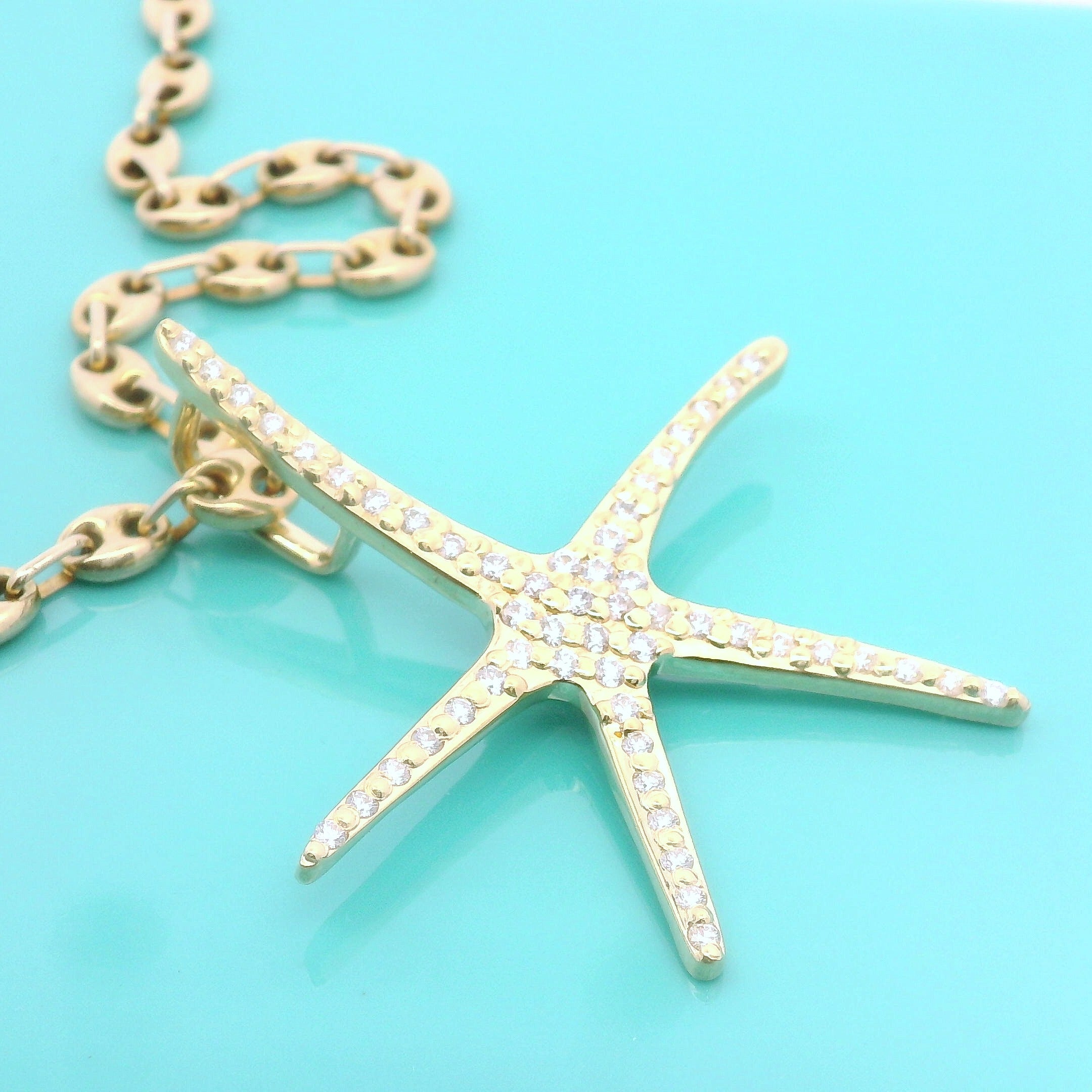 Custom mdade Gold starfish pendant necklace on a turquoise background