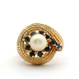 Gold ring with a pearl and blue gemstones on a white background